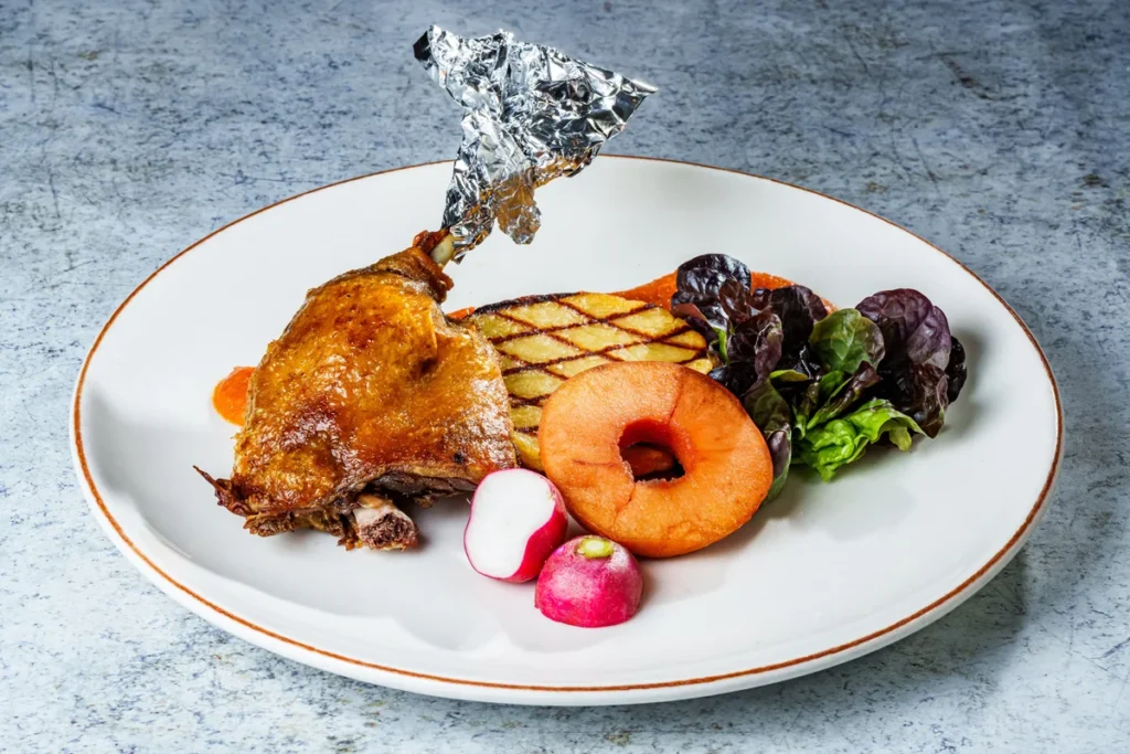 Crispy duck leg roasted on a bed of apples, with potato roundel